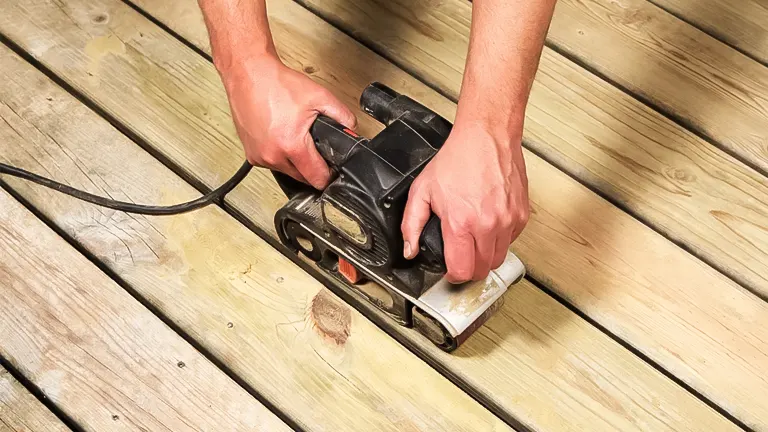 Person using a belt sander on a hardwood floor