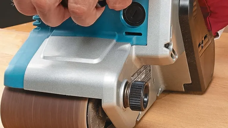 Close-up of a belt sander being used on a light-colored hardwood floor