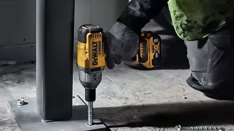 Person using a yellow and black power drill on a metal pole.