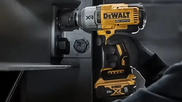 Hand holding a DeWalt power drill on a black background.