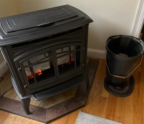 Black wood stove with a fire inside and a bucket next to it.