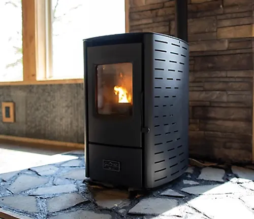 Black wood-burning stove in a room with a stone floor and wooden walls.