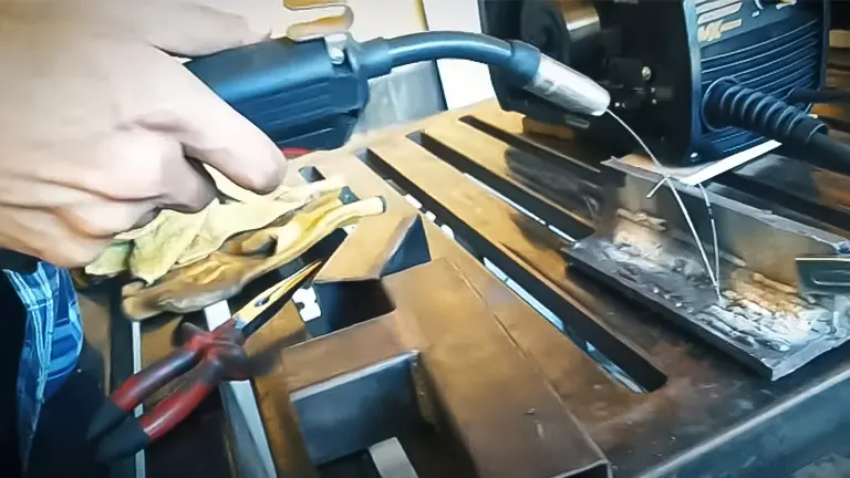 Person in blue shirt using Grizzly G0880 85A Stick Welder on a metal workbench.