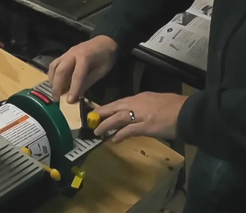 A person using a Grizzly H7760 Combo Belt Sander/Grinder on a wooden surface in a workshop