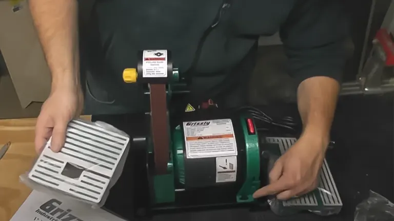 Grizzly H7760 Combo Belt Sander/Grinder in use on a workbench, with a person’s hands visible in the background
