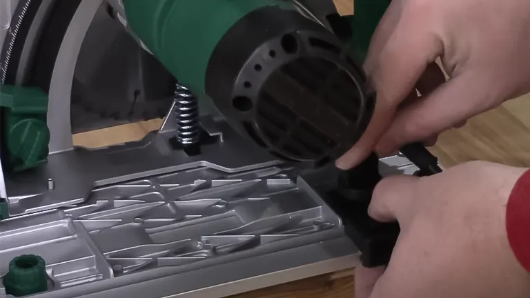 Hand holding a green power tool over a gray workbench.