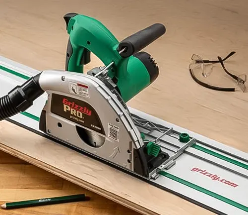 Green and gray circular saw with safety glasses and pencil on wooden surface.