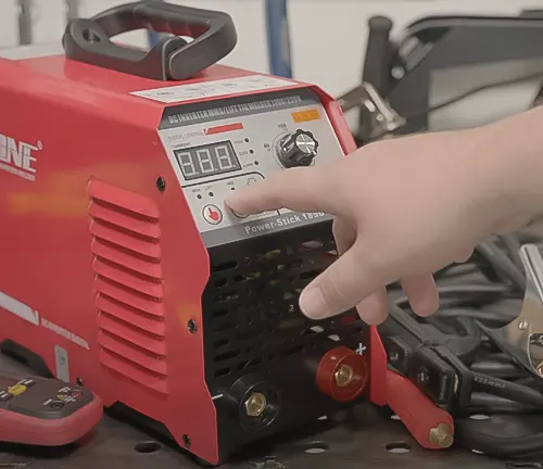 Hand adjusting settings on a red HONE Stick Welder 110V/220V Actual 140Amp ARC Welder Machine