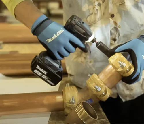 Person using Makita 18V XDT19 Brushless Cordless Impact Driver on wooden pipe.