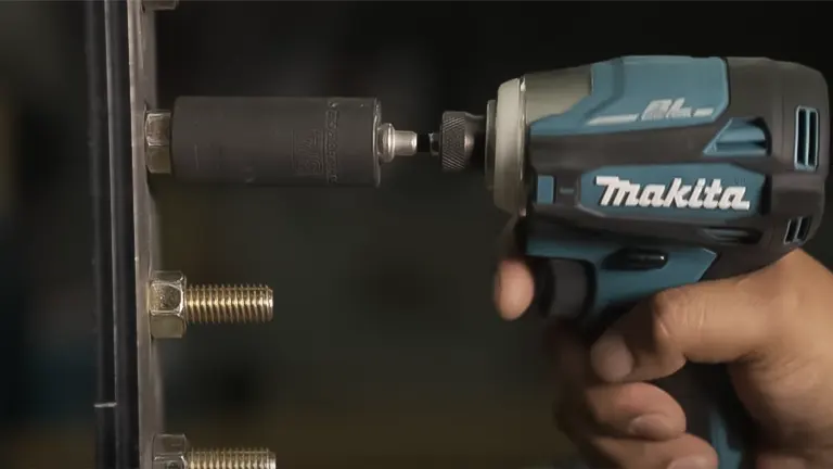 Hand holding Makita 18V XDT19 Brushless Cordless Impact Driver in a workshop.