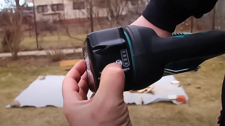 Close up of a person’s hand holding a Makita DJR185Z Cordless Reciprocating Saw LXT 18V Li-Ion in a yard