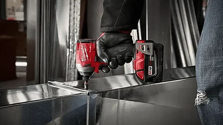 Person using a Milwaukee T32196R M18 Recon BL Hex Impact Driver  on a metal surface.