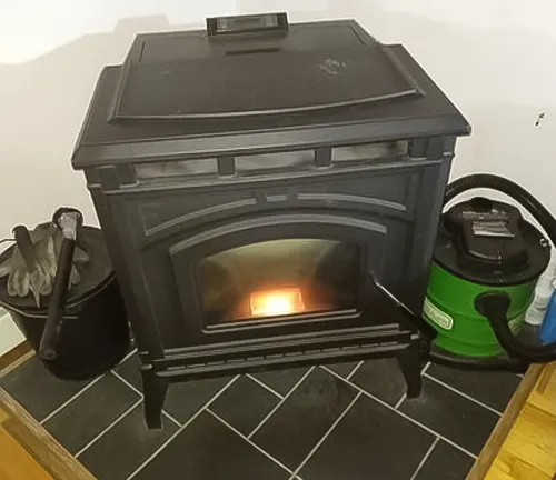 Burning wood stove next to a green vacuum cleaner and black bucket