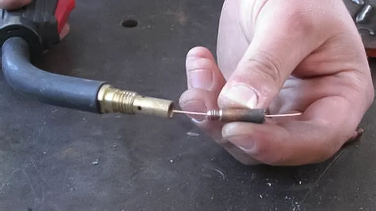 Close up of a hand holding a welding machine nozzle with wire sticking out