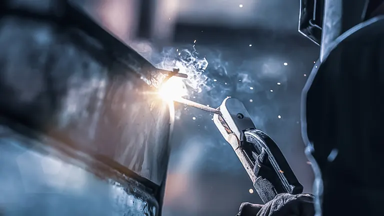 Close up of a welder working on a metal object with sparks flying