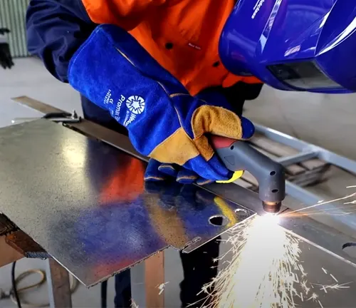 Worker using a WELDCLASS Cut-force WC-43P Plasma Cutter to cut metal in a workshop.