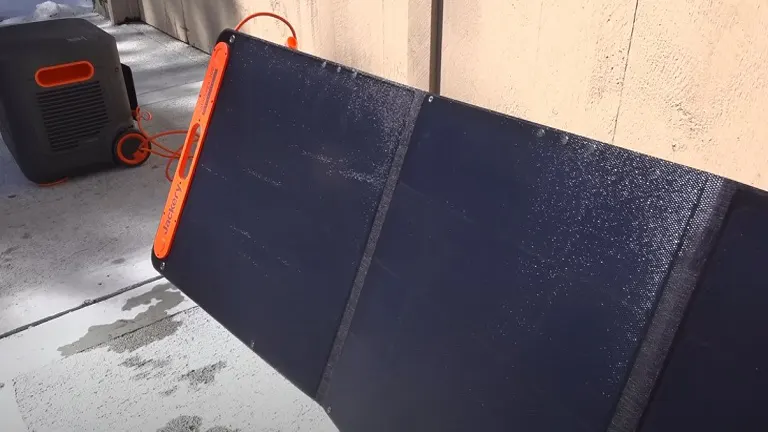 A blue and orange foldable solar panel on a concrete sidewalk.