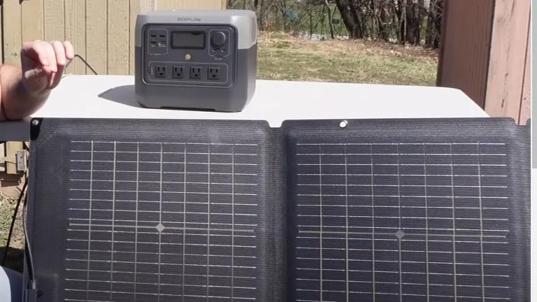 A portable solar panel and a gray power station on a white table.