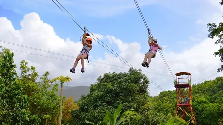 Two people zip-lining over lush greenery at El Yunque National Forest
