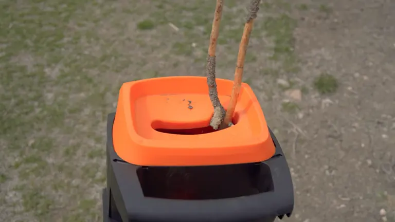 Branch being inserted into an orange and black WEN 5 Amp Rolling Electric Wood Chipper and Shredder