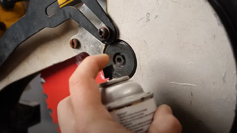 Close-up of hand adjusting miter saw with spray can