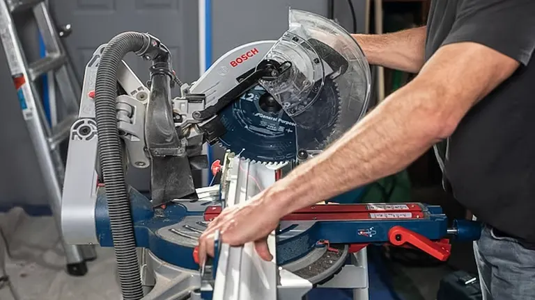 A person using a BOSCH PROFACTOR 18V 12" Dual-Bevel Glide Miter Saw to cut a piece of wood in a workshop