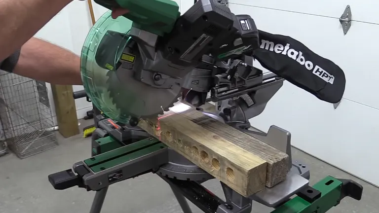 Person using a Metabo HPT 36V MultiVolt 10” Dual-Bevel Sliding Miter Saw to cut a wooden plank in a workshop