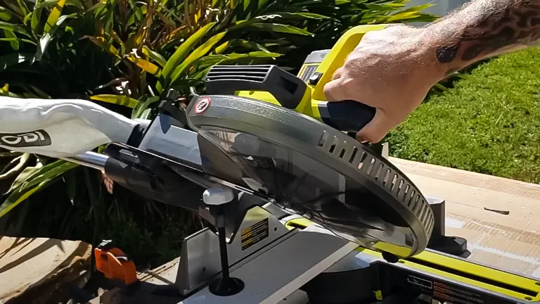 A person using a Ryobi 12” Sliding Compound Milter Saw in a garden setting