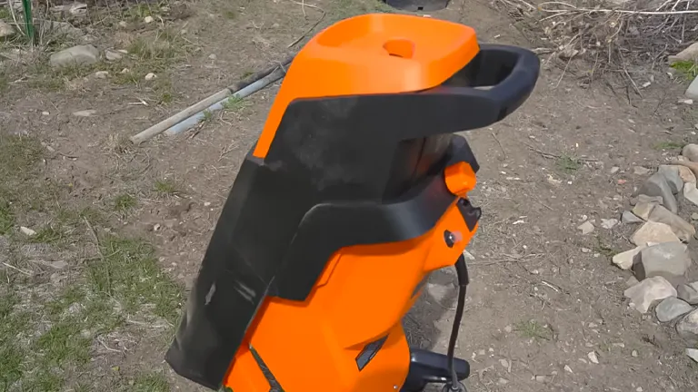 Orange and black WEN 5 Amp Rolling Electric Wood Chipper and Shredder on grassy ground with cut branches in the background