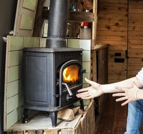 Man infront of woodstove pointing wood stove
