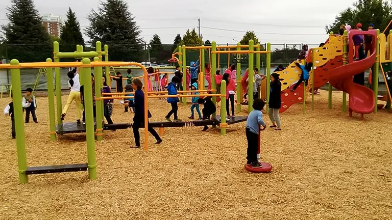 a well-equipped playground filled with children playing on various equipment such as climbing structures, swings, and a slide