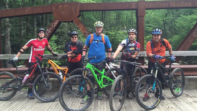 group of cyclists with their mountain bikes standing on a wooden bridge in Pisgah National Forest