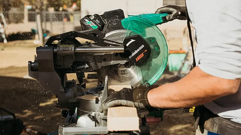 Person using a Metabo HPT 36V MultiVolt 10” Dual-Bevel Sliding Miter Saw to cut wood outdoors