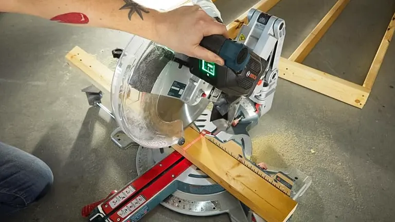 Person using a BOSCH GCM18V-12GDCN PROFACTOR 18V 12” Dual-Bevel Sliding Miter Saw to cut a wooden plank