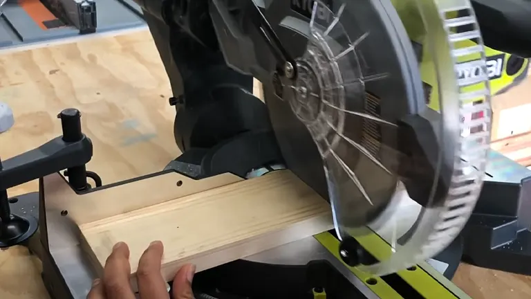 Miter saw cutting through a wooden plank in a workshop