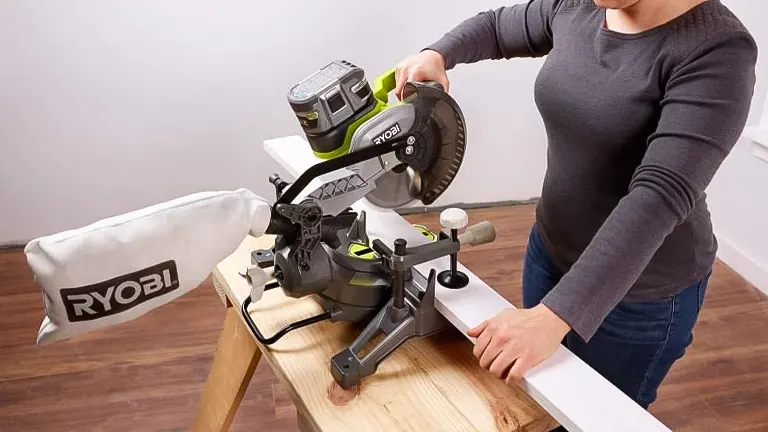 Person using a green and black Ryobi P553 18V ONE+ 7-1/4” Compound Miter Saw on a wooden table