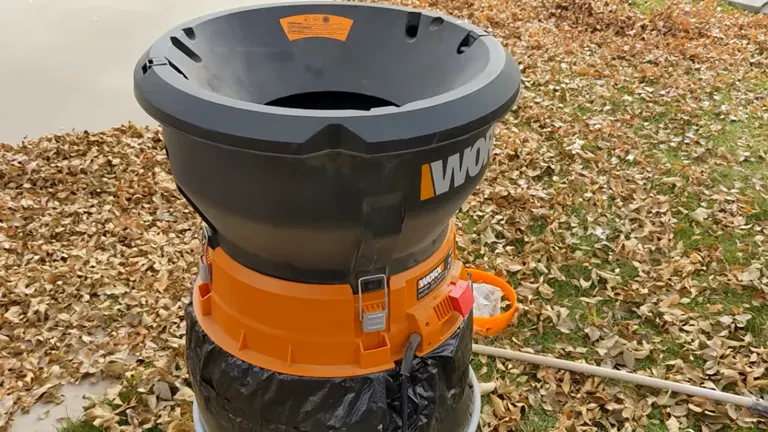 Worx WG430 Electric Leaf Mulcher placed outdoors on a lawn covered with dry leaves