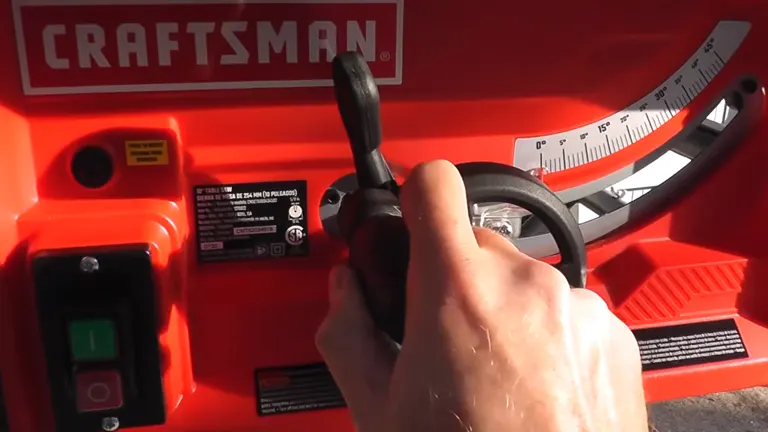 Close-up of a person’s hand adjusting the black handle on a bright red Craftsman portable table saw