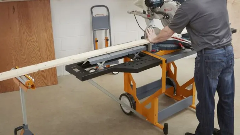 Person using an orange and black Bora Portamate PM-8000 Miter Saw Stand in a workshop