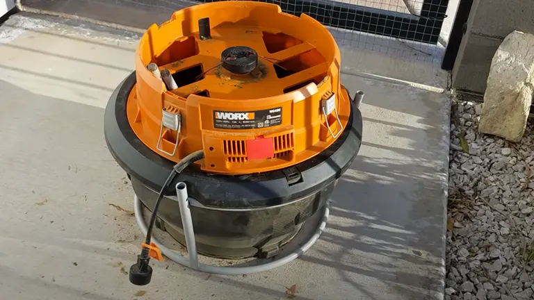 Worx WG430 Electric Leaf Mulcher placed outdoors on a concrete surface next to gravel and a large rock