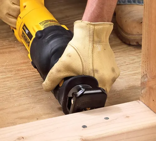 A person using a yellow reciprocating saw to cut through a wooden board