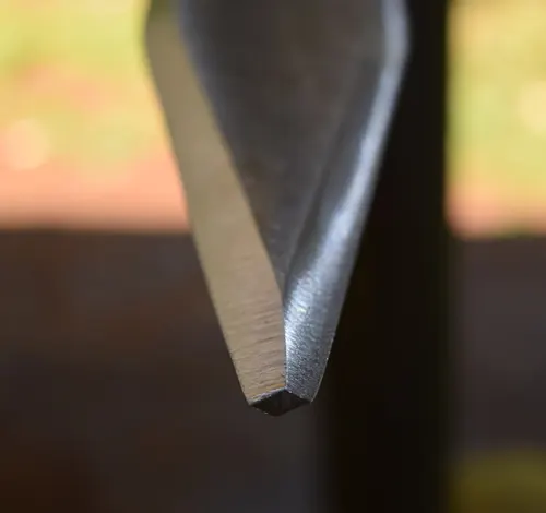 Close-up of a sharp, steel sword tip in an outdoor setting