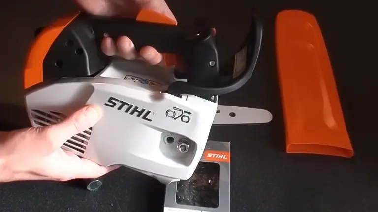 Hands holding a Stihl MS 151 TC E Chainsaw with accessories nearby