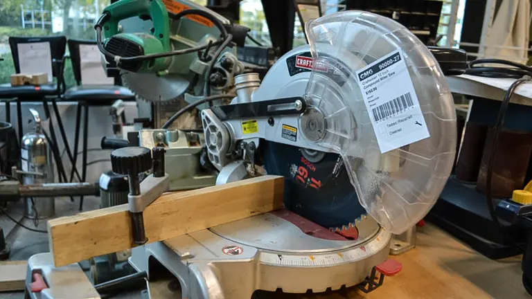 Miter saw with red blade and yellow label on a workbench, set for adjustment