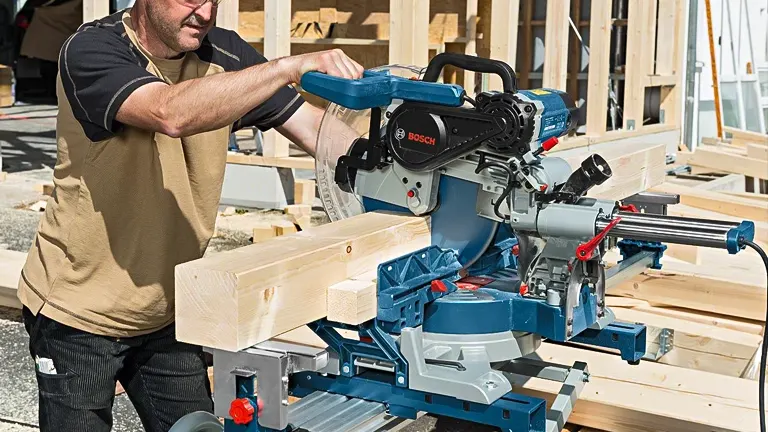 Person using Bosch GCM12SDE 12” Professional Glide Miter Saw to cut wood in a workshop