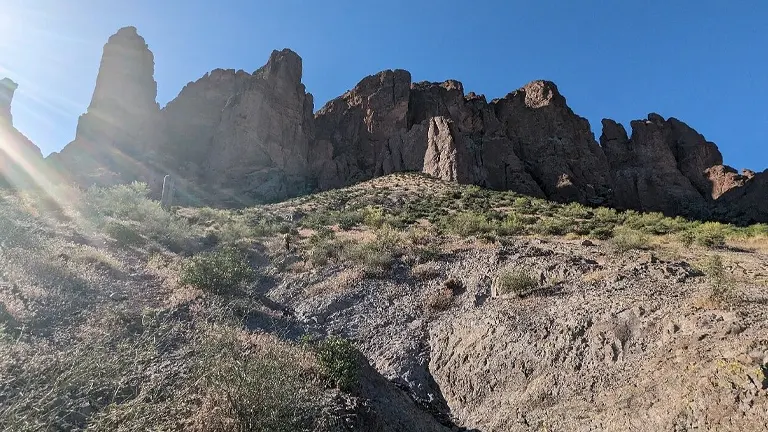 Sunlit, rugged terrain of Tonto National Forest with towering rock formations and sparse vegetation under a clear sky