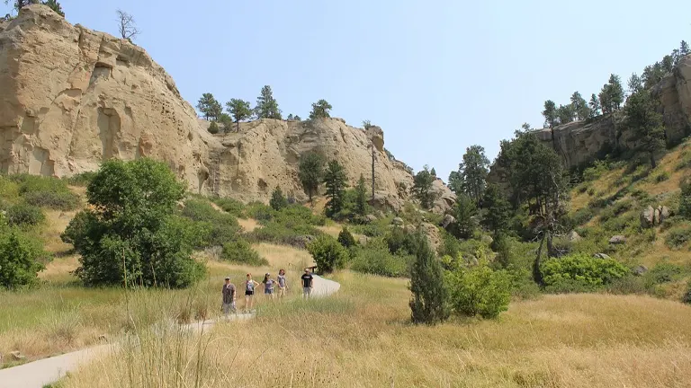 Visitors walking on a trail at Pictograph Cave State Park amidst rocky formations