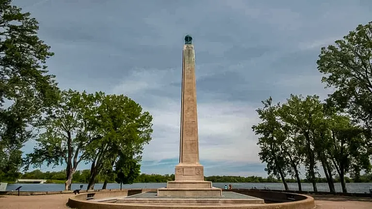 Tall monument at Presque Isle State Park, surrounded by trees under a cloudy sky