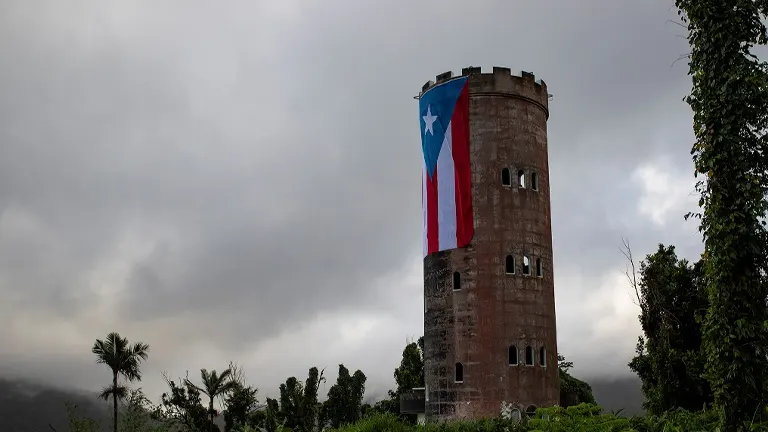 Stone tower with Puerto Rican flag in El Yunque National Forest under a cloudy sky