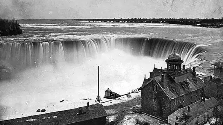Historic black and white image of Niagara Falls with adjacent buildings